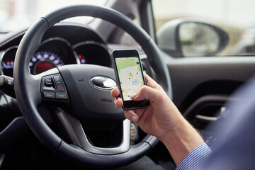 Fototapeta premium Let your GPS guide you. Closeup shot of a driver in a car using a cellphone to find directions.