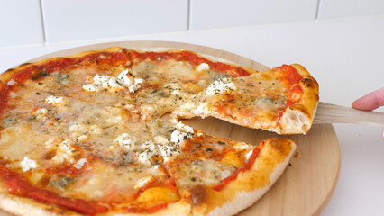 Taking a piece of pizza from a wooden plate