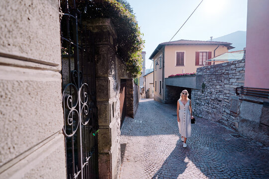 Fototapeta Traveling by Europe. Happy young woman in dress walking by streets in italian old town.