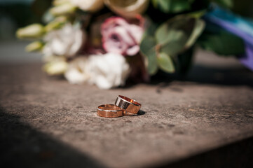 A pair of gold wedding rings, a bouquet of flowers in the background