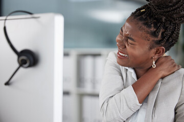 Dont allow your back pain to get the better of you. Shot of a young female call center agent suffering from back pain in an office at work.