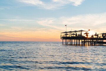 beautiful sunset on the sea. pier with umbrellas and sunbeds for vacationers