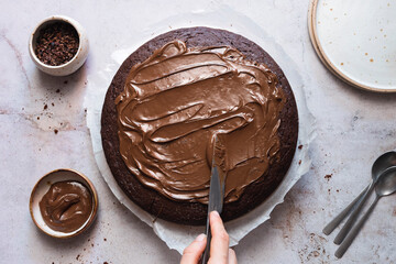 Icing being spread on to a chocolate cake