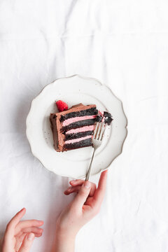 Raspberry and chocolate cake slice, on plate with fork.