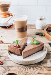 Chocolate cheesecake with pecans and mint, coffee cup on rustic wooden background.