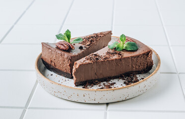 Chocolate cheesecake with pecans and mint, coffee cup on white background.