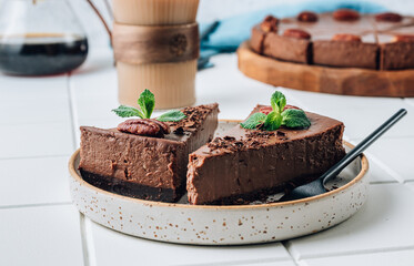 Chocolate cheesecake with pecans and mint, coffee cup on white background.
