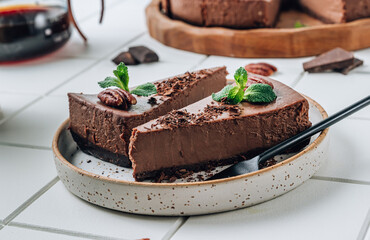 Chocolate cheesecake with pecans and mint, coffee cup on white background.