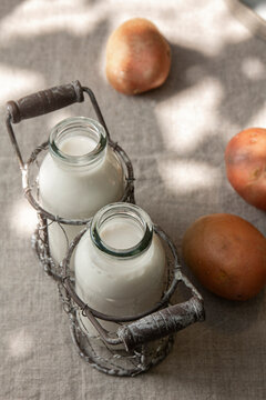 Potato milk in bottle and potatoes on the table in garden. Alternative non dairy healthy vegetarian drink. Sunlight effect