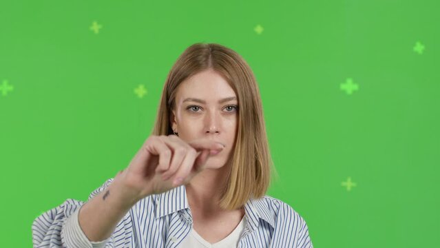 Close-up of young woman swipes finger at display of phone. Female over green screen background, Chroma Key. 4k video footage