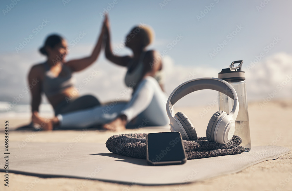 Wall mural This is all you need to have a good workout. Shot of a cellphone, headphones, towel and water bottle on the beach.