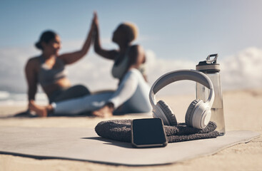 This is all you need to have a good workout. Shot of a cellphone, headphones, towel and water bottle on the beach.