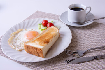トーストや卵を調理した物をお皿に盛り付けた朝食のイメージ