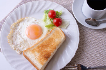 トーストや卵を調理した物をお皿に盛り付けた朝食のイメージ