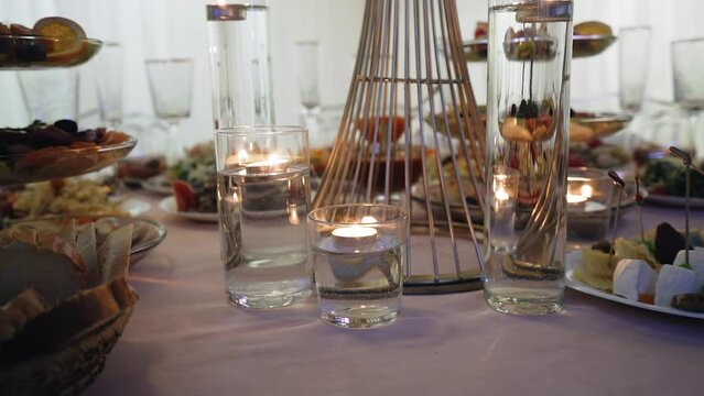 There are candles on the table and delicious food on plates. Shooting an evening meal