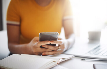 Staying connected is important at the office. Closeup shot of an unrecognizable female designer using a cellphone in her home office.