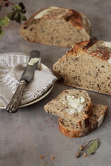 A composition of food in a dark rustic style, a sliced loaf of bread and pieces of bread with butter, a plate with a knife on a linen napkin, culinary magazine / book, culinary / food photography.
