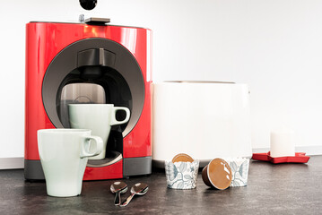 Red capsule coffee maker and light green cups on a dark gray countertop in a kitchen, coffee spoons in the kitchen of a vacation rental apartment
