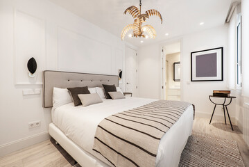 Double bed with upholstered headboard in matching fabric with blankets and rugs in a vacation rental bedroom
