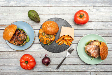 Set of three burgers of assorted flavors, with jalapeños, french fries, fried bacon and Iberian ham, crispy onion, cheddar cheese, tomato and red onion, avocado and fork