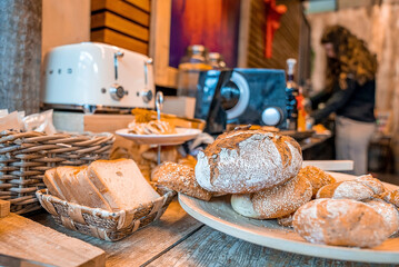 Assorted fresh breads in plate and basket on wooden table in hotel, Various breads in plate on wooden table