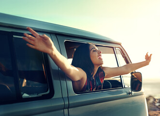 Life is the greatest road worth traveling. Shot of a young woman leaning out of her vans window with her arms outstretched.