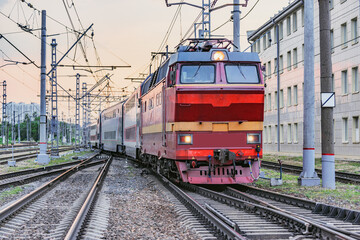 Fototapeta na wymiar Passenger retro electric czech locomotive with train departs from the station at sunset time.