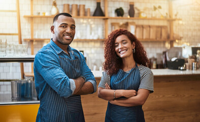 Were ready to make a success of the day. Portrait of two young entrepreneurs standing in their cafe.
