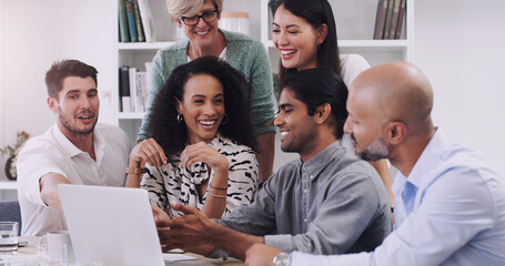 Teamwork has the power to inspire positive change. Shot of a group of businesspeople using a laptop in a modern office.