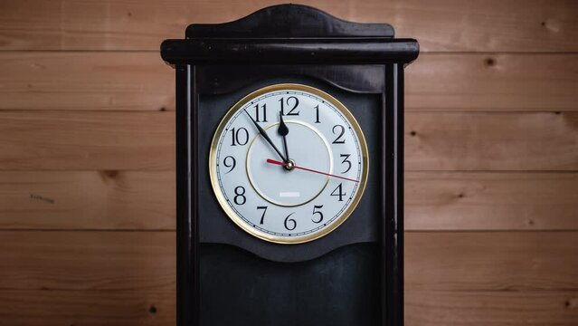 Timelapse of vintage clock with full turn of time hands at 12 pm or am on wooden background. Old Retro wall clock with white circular dial. Old-fashioned antique clock. Arrows second, minute, and hour
