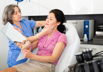 Professional cosmetician explaining future treatment to female patient