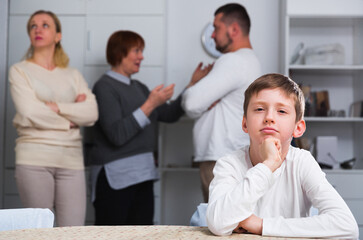 Sad desperate little boy during parents quarrel in home interior.
