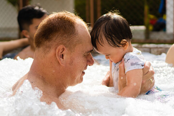 latino grandpa in the jacuzzi with his baby grandson putting heads together - obrazy, fototapety, plakaty