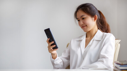 Asian woman smiling and hand holding mobile phone to find out online what interests them. searching information data on internet networking.