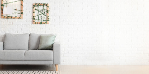Stylish sofa near white brick wall with space for text