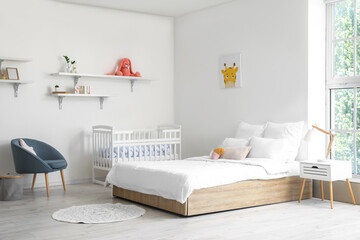Modern interior of cozy room with big bed and comfortable baby crib