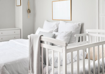 Comfortable baby crib in interior of cozy bedroom