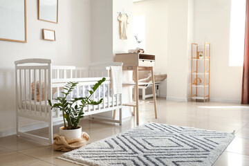 Modern interior of cozy room with comfortable baby crib and high table in studio apartment