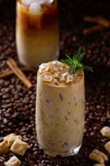 Iced latte coffee. Cup of Iced latte coffee, milk tea on dark coffee seeds background. Could Coffee with cardamom and cinnamon.
