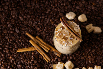 Iced latte coffee. Cup of Iced latte coffee, milk tea on dark coffee seeds background. Could Coffee with cardamom and cinnamon.