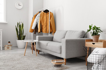 Interior of light room with grey sofa and warm jackets