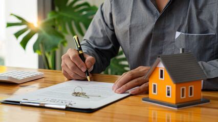Businessman's signature on documents, checks, and documents in real estate investment projects on the desk. Sales report on the mortgage agent market in real estate concepts.
