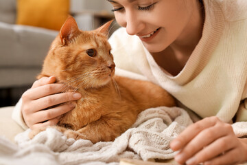 Woman with cute ginger cat at home on autumn day