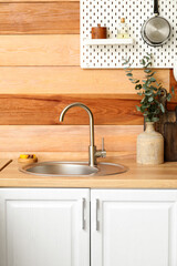Counter with sink and vase near wooden wall