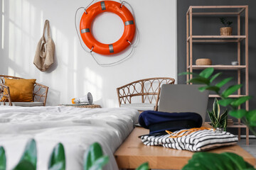Interior of light bedroom with ring buoy and sailor's uniform
