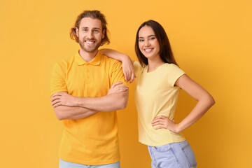 Young couple in stylish t-shirts on yellow background
