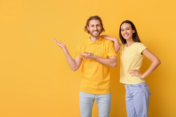 Young couple in stylish t-shirts on yellow background