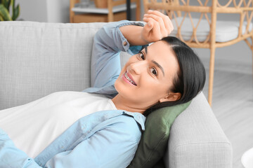 Beautiful woman with dental braces lying on sofa at home