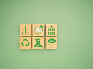 Net-zero greenhouse gas emissions target. Wooden cubes with green icons over a green background