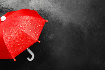 Red umbrella with water drops on dark background, closeup